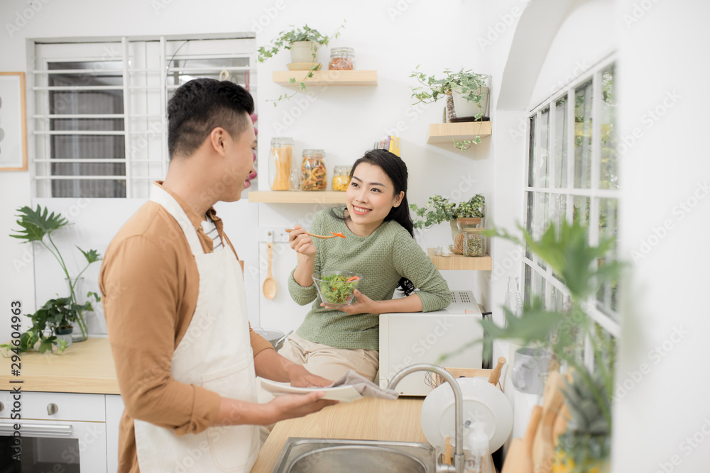 一对亚洲夫妇一大早就在厨房吃早餐，玩得很开心。