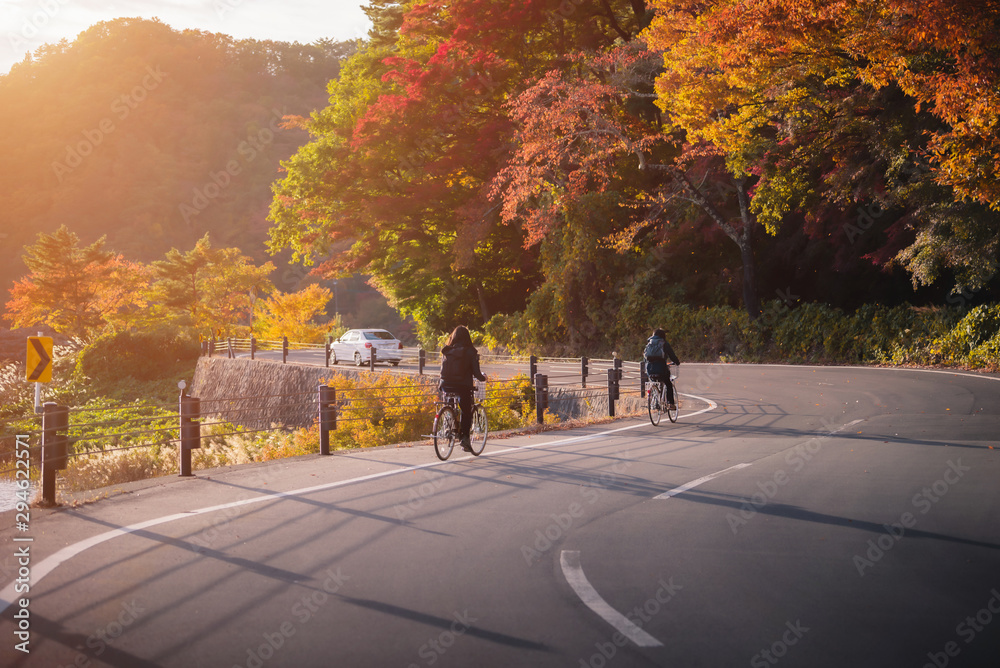 日落时分，在日本富士河湖河口湖附近的秋叶公路上骑自行车的游客