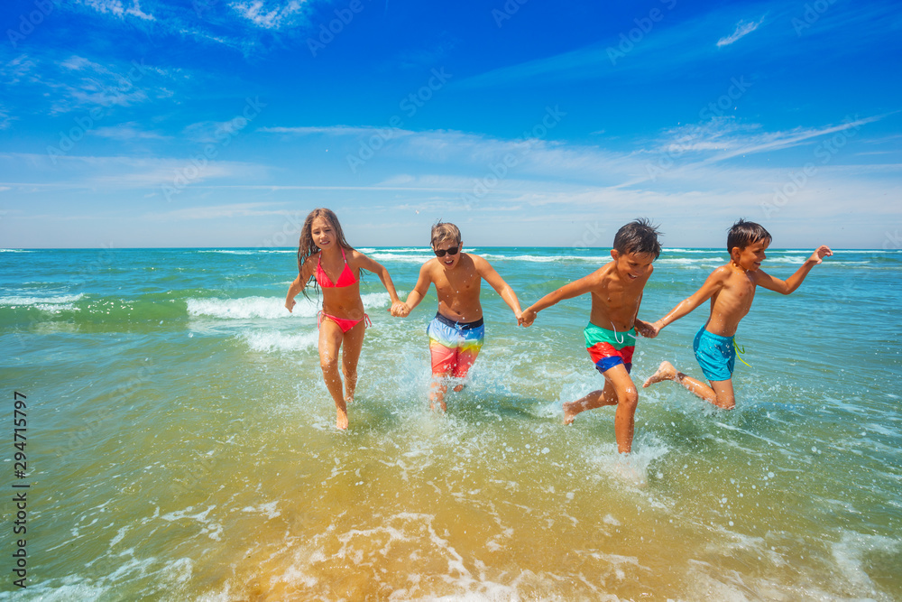 Group of cute kids run from sea holding hands