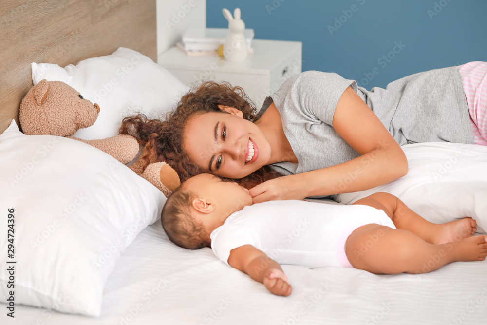 Young African-American woman and her sleeping baby on bed