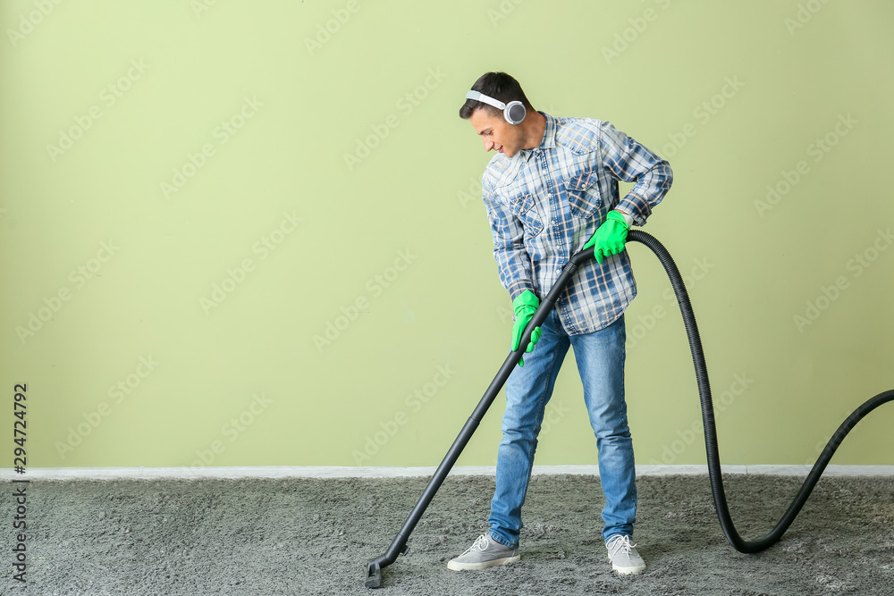 Young man hoovering carpet at home