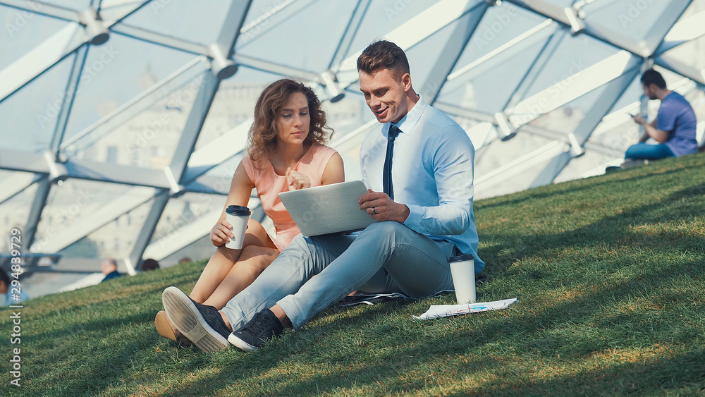 Young people with laptop on a grass