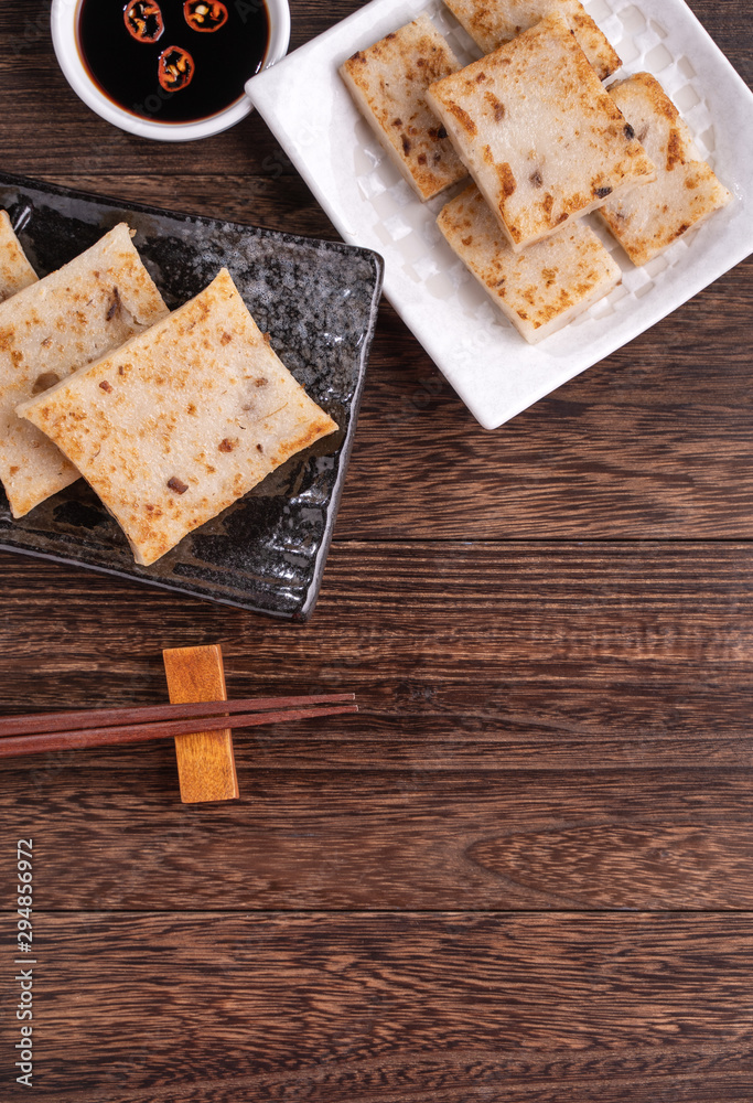 Delicious turnip cake, Chinese traditional local radish cake in restaurant with soy sauce and chopst