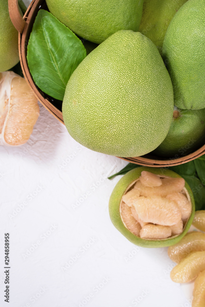 Fresh pomelo, pummelo, grapefruit, shaddock on white cement background in bamboo basket. Autumn seas