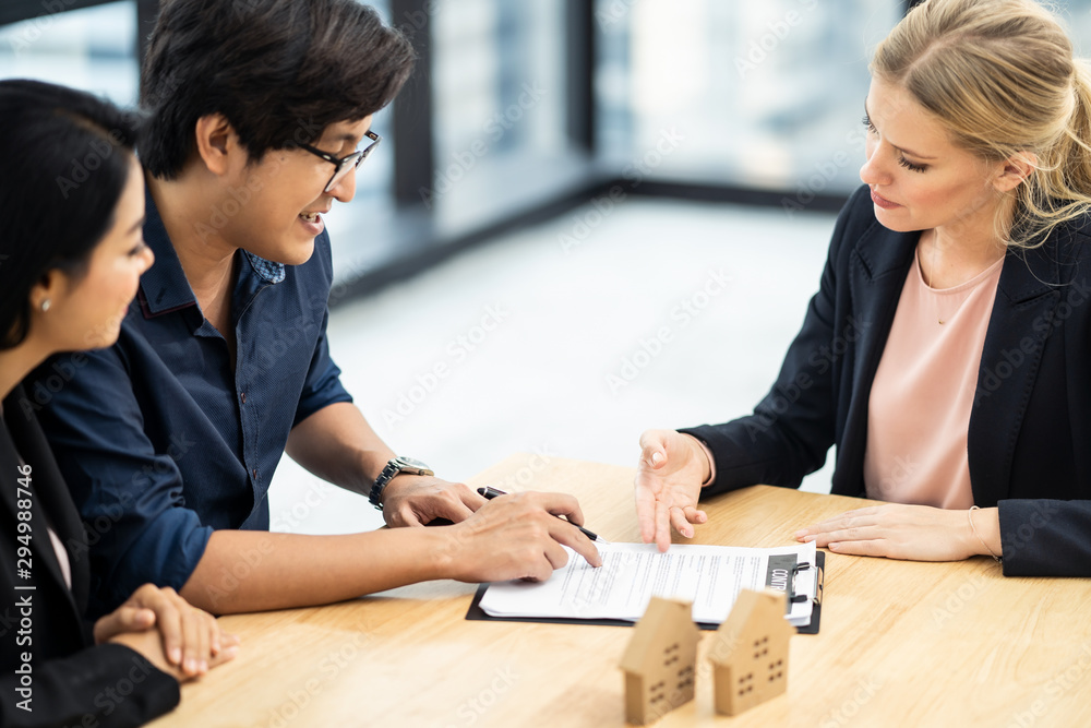 Beautiful Caucasian home properties female sale agent giving contract paper to couple husband and wi