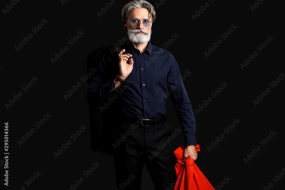 Portrait of stylish Santa Claus with bag on dark background