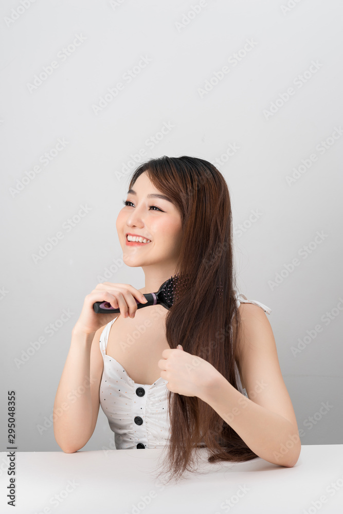 Hair care. Young Asian girl combing hair with finger isolated on white background