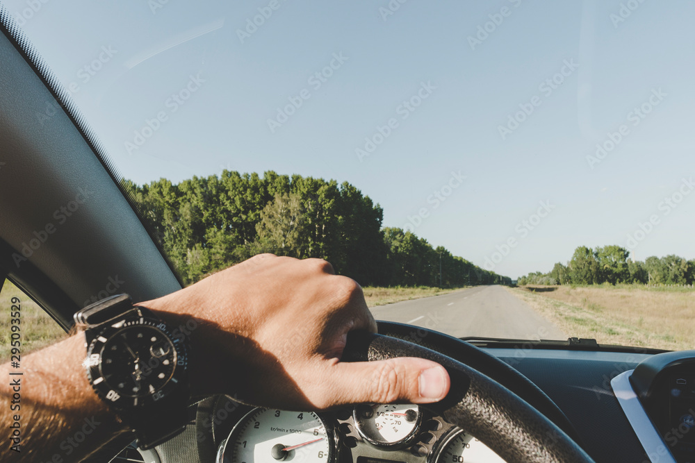 A man is driving on the road outside the city. inside view. mans hand with with a smart watch on st