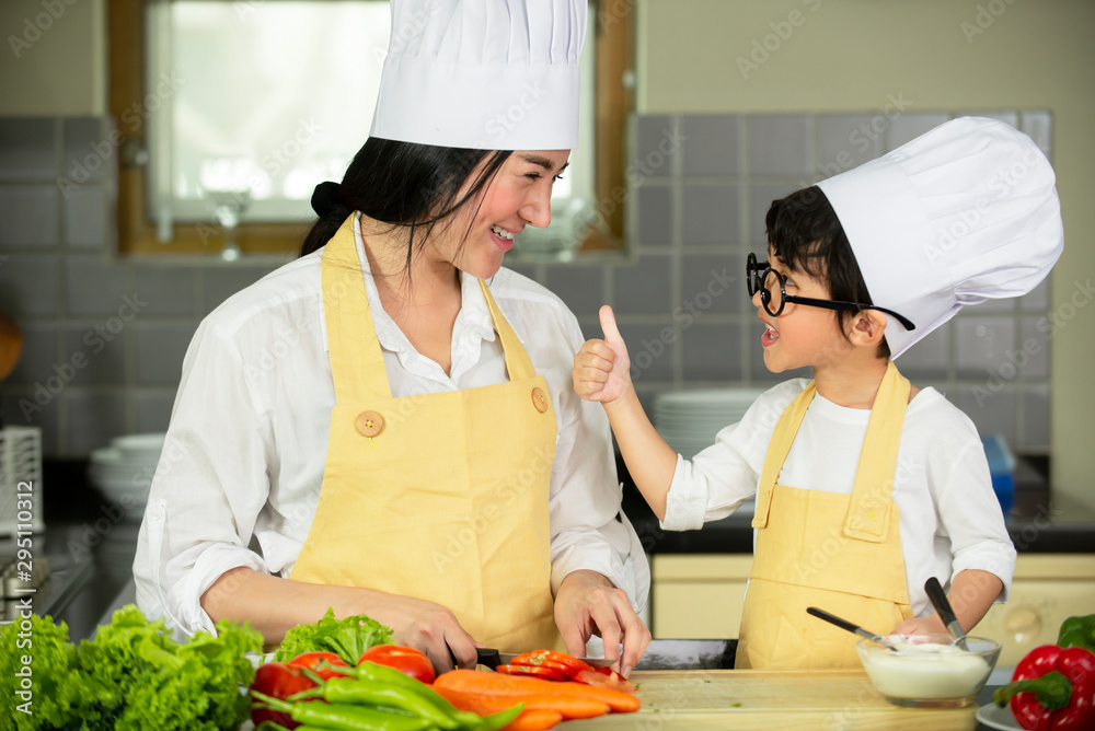 Happy Asian mother and son  in chef hats preparing  healthy food in kitchen at home , family healthy