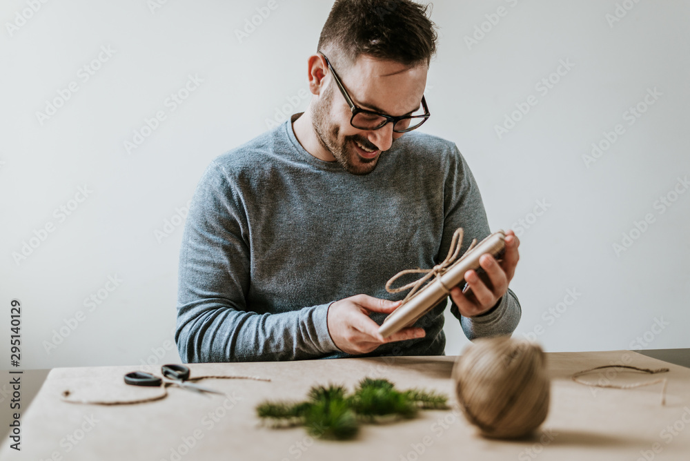 一个有魅力的男人拿着他包好的礼物微笑着。