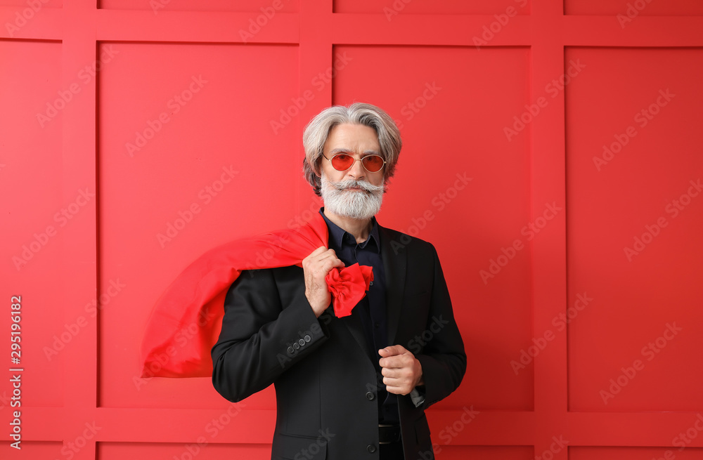 Portrait of stylish Santa Claus with bag on color background