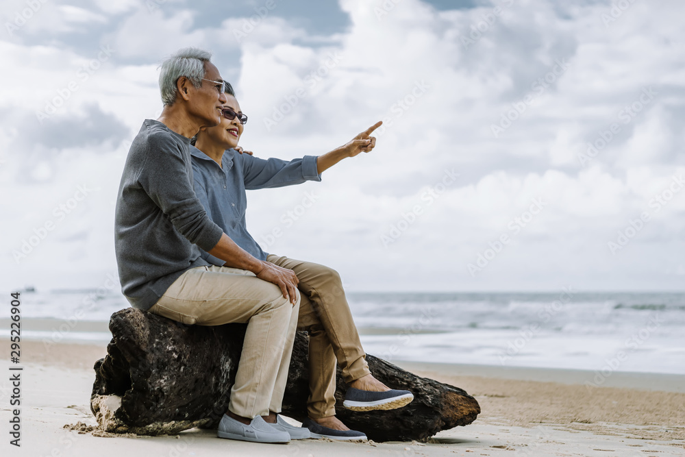 亚洲老年夫妇或老年人周末度假时在海滩散步和坐着