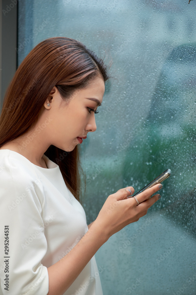 雨天一位严肃女性在家使用智能手机的侧视图