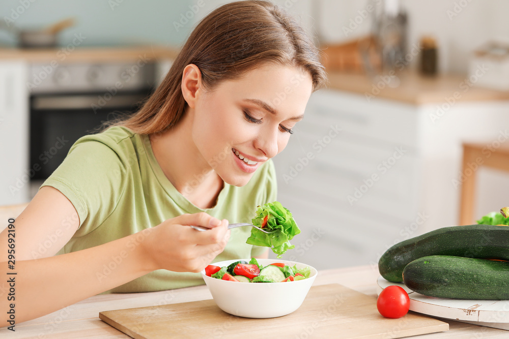 年轻女性在厨房吃健康蔬菜沙拉。饮食理念