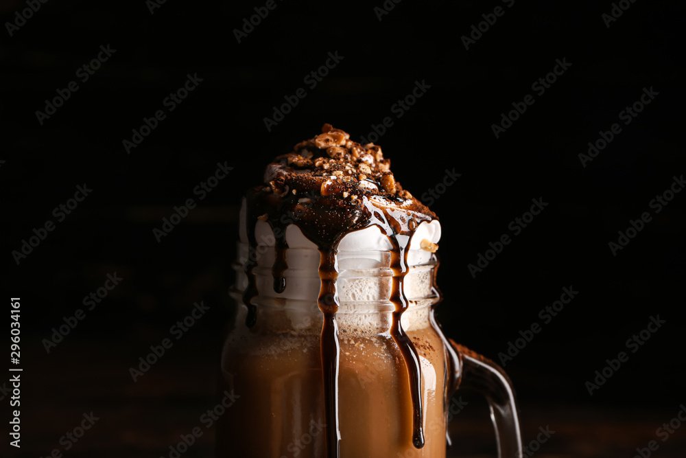 Mason jar of tasty frappe coffee on dark background, closeup