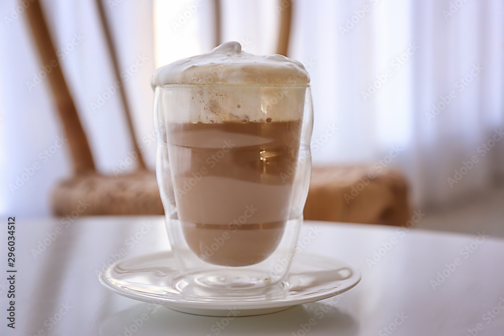 Glass of tasty frappe coffee on table in cafe