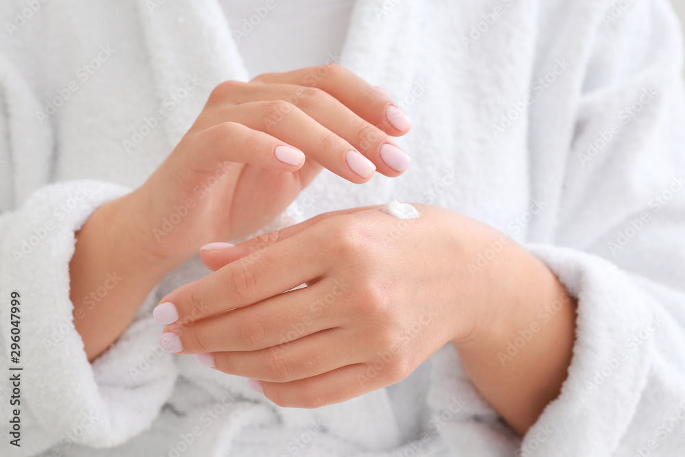 Young woman applying hand cream, closeup