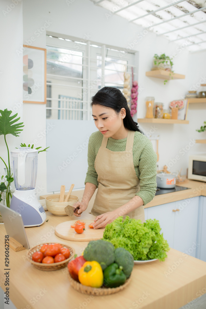 健康食品，饮食理念。亚洲女人晚餐做蔬菜沙拉，切成熟的西红柿