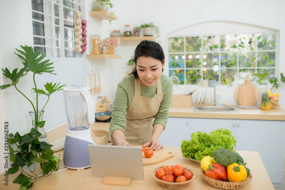 厨房里的女人在数字平板电脑上遵循食谱