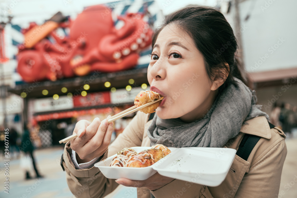 中国亚洲年轻女旅行者在大阪津天阁街头吃饺子面糊。女孩旅游