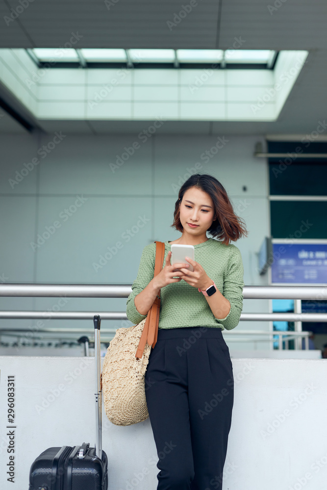 一名亚洲女子在亚洲机场等待时正在检查她的智能手机。