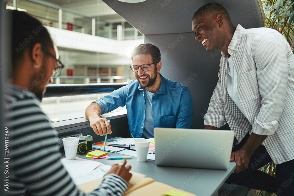 Laughing designers working inside of an office meeting pod