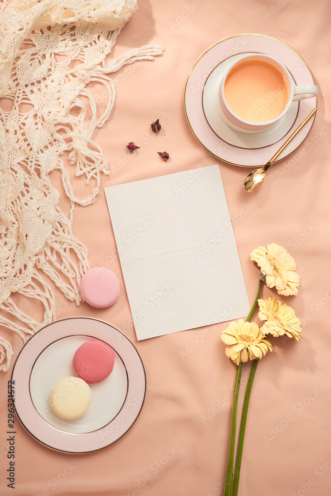 Envelope, flowers, and macarons with cup of tea on light background