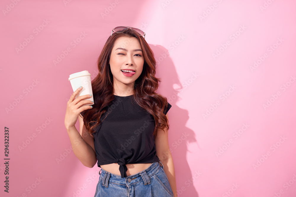 Fashion pretty woman with coffee cup wearing black  clothes over colorful pink background