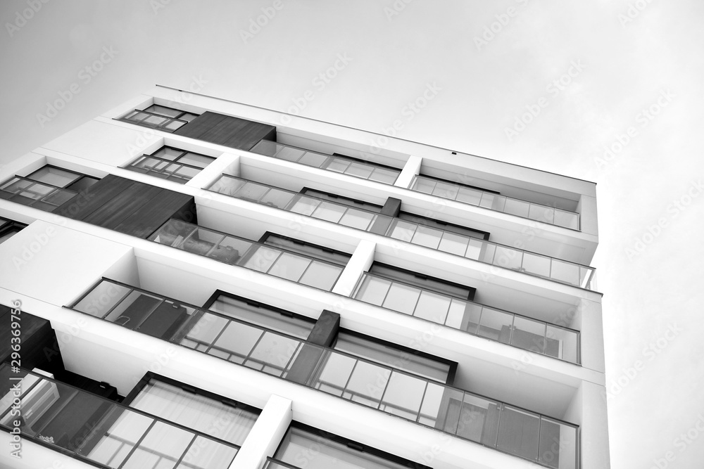 Fragment of a facade of a building with windows and balconies. Modern home with many flats. Black an