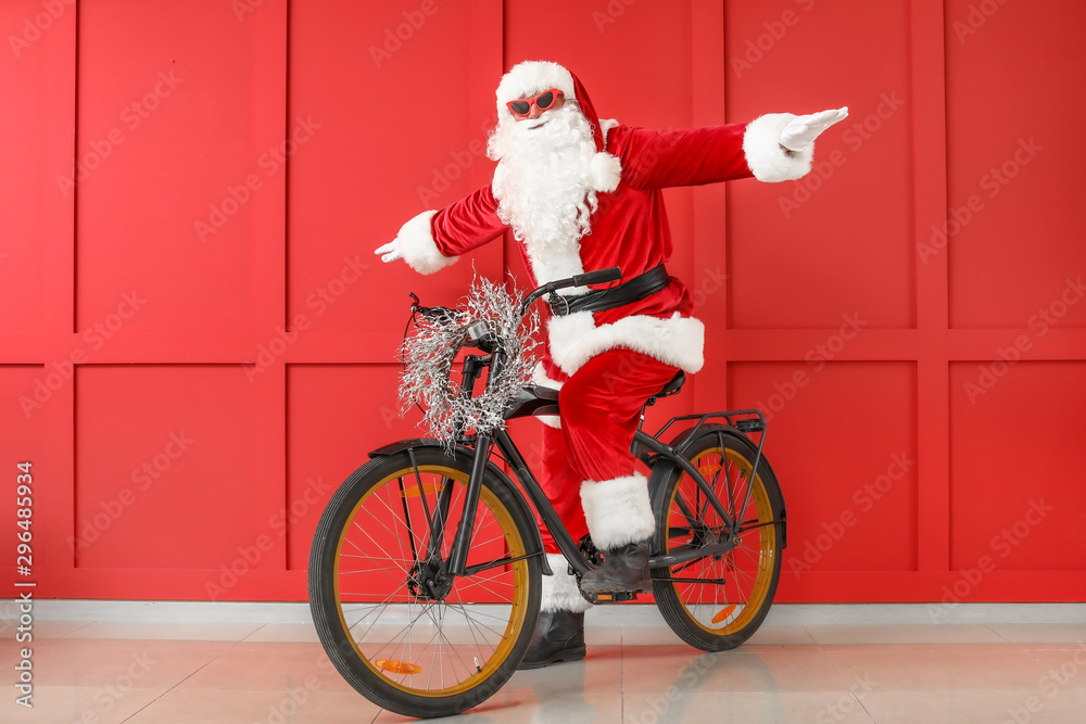 Santa Claus with bicycle on color background