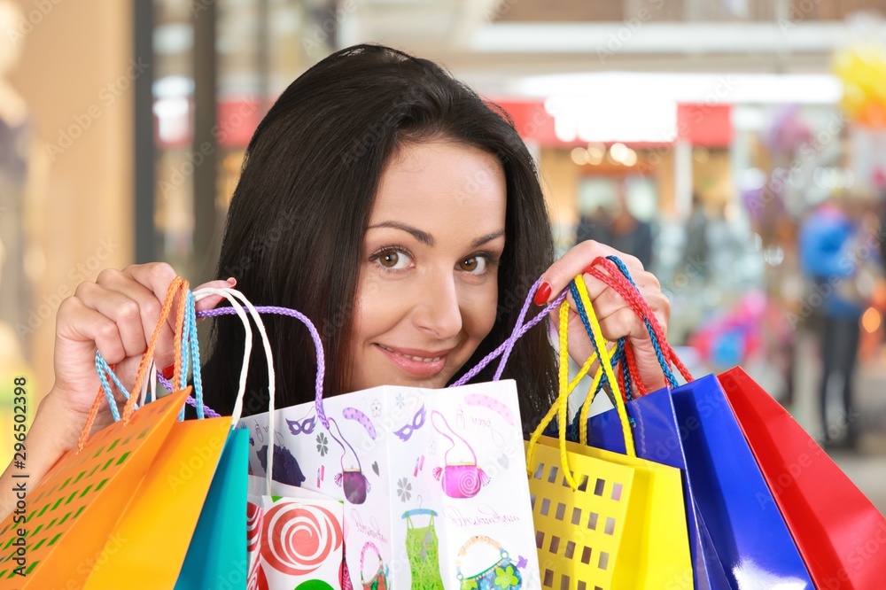 Young woman with shopping bags on mall background