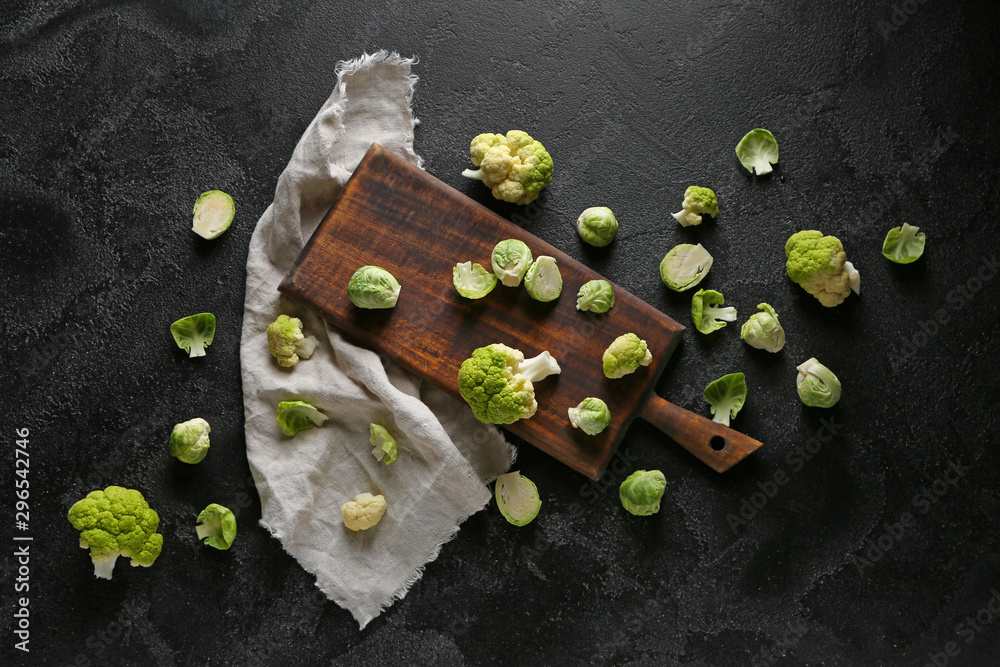 Board with different fresh cabbage on dark background