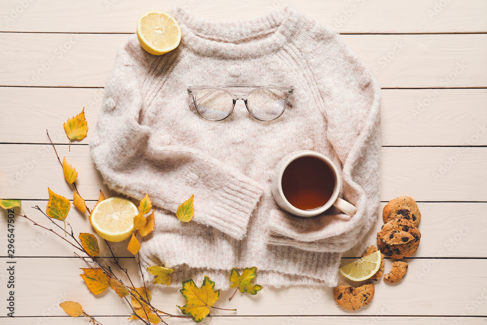 Beautiful autumn composition with warm sweater and cup of tea on wooden background