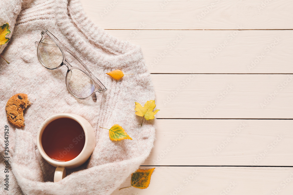 Beautiful autumn composition with warm sweater and cup of tea on wooden background