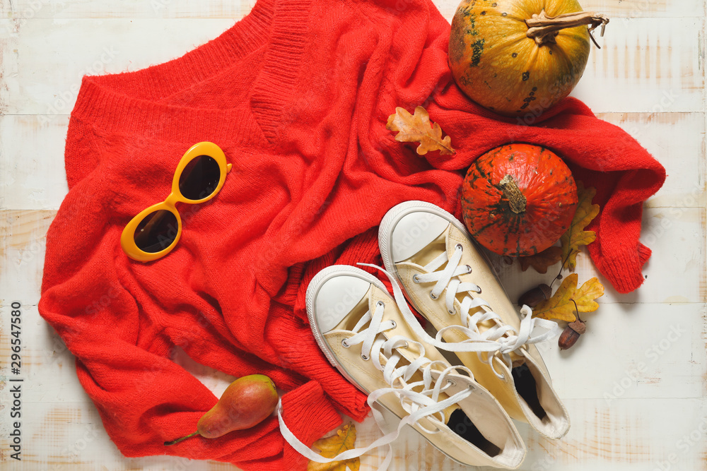 Beautiful autumn composition with clothes and pumpkins on light background