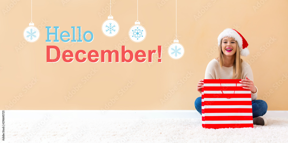 Hello December message with happy woman with Santa hat holding a shopping bag