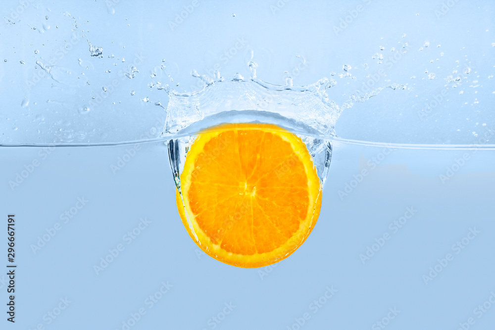 Falling of orange piece into water on light background