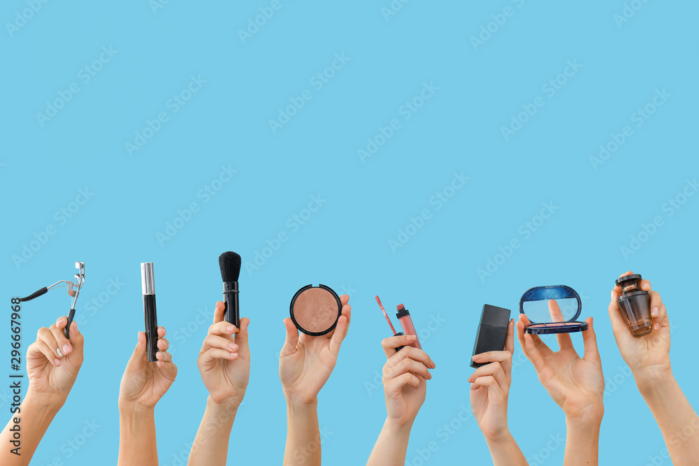 Many hands with decorative cosmetics on color background