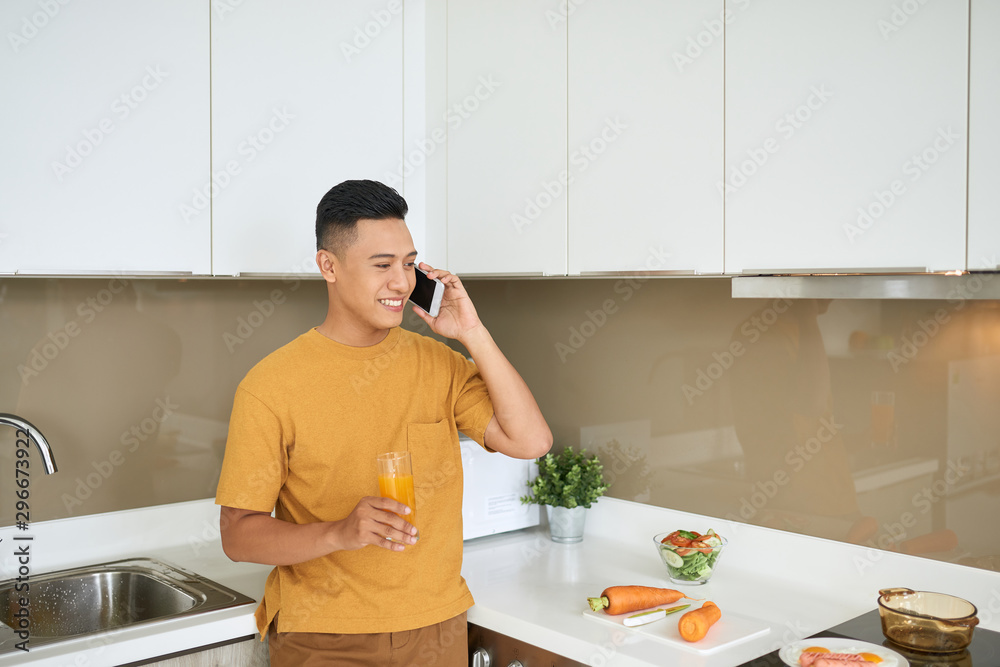 Handsome bachelor 30s talking on mobile phone, while having breakfast in morning