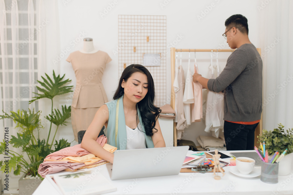 Fashion designers at work.  Handsome male designer choosing design while his colleague working with 