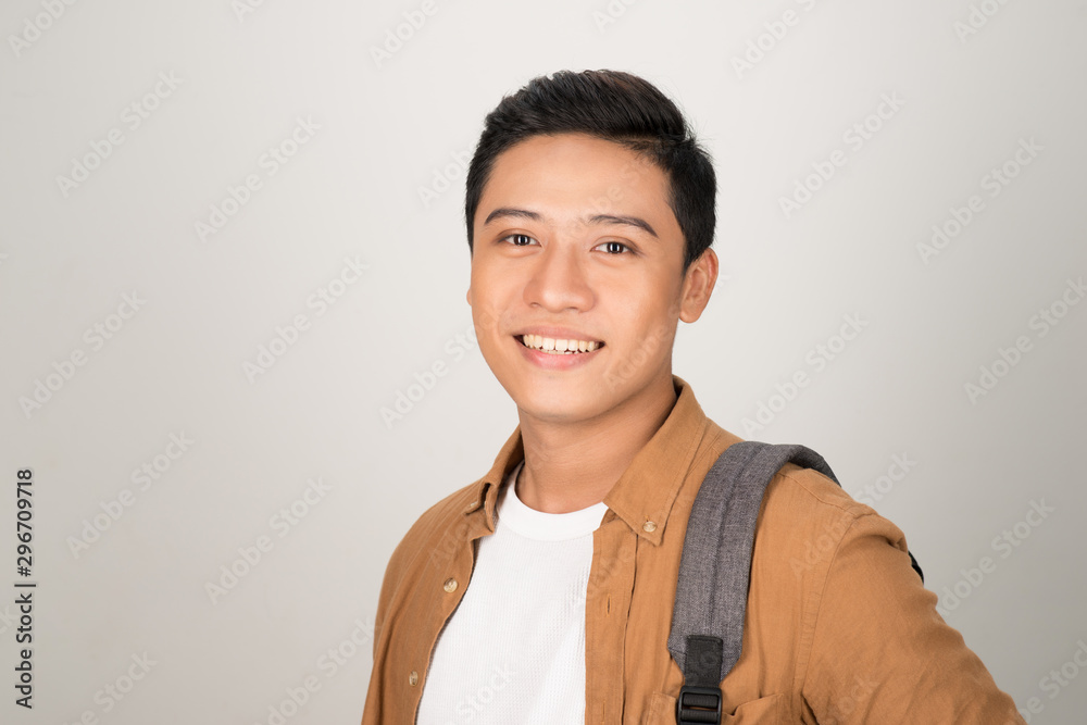 Portrait of handsome Asian student carrying backpack isolated on white background