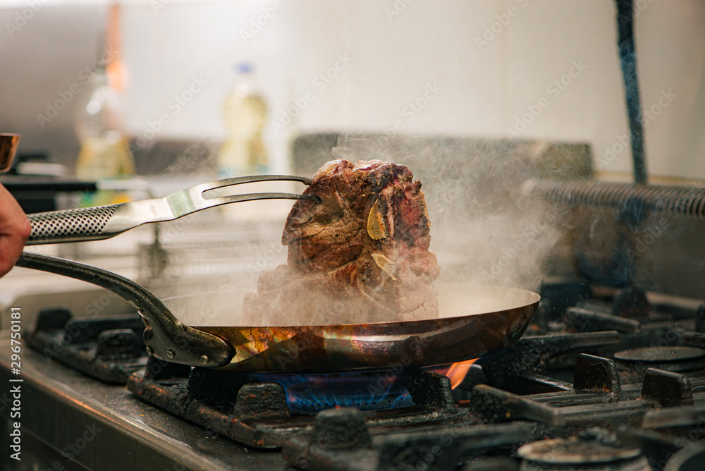 Steaming t-bone steak in a pan.