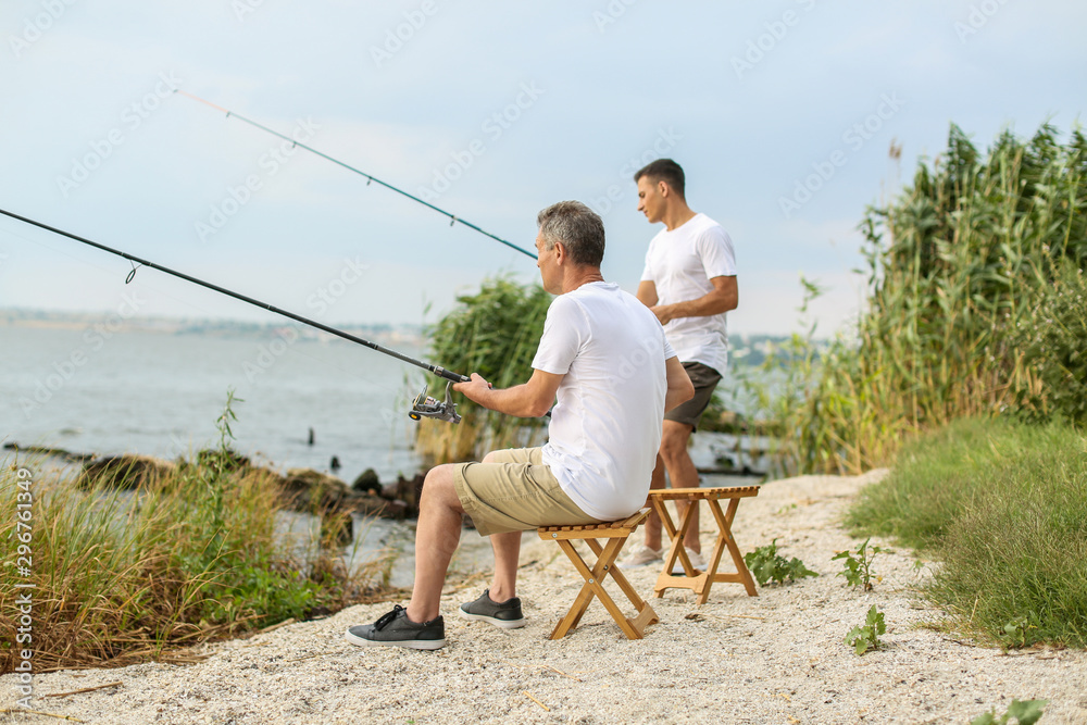 Young man and his father fishing on river