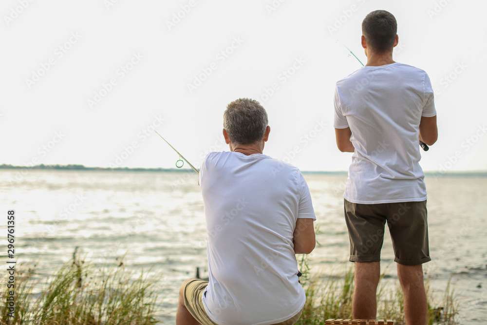 Young man and his father fishing on river