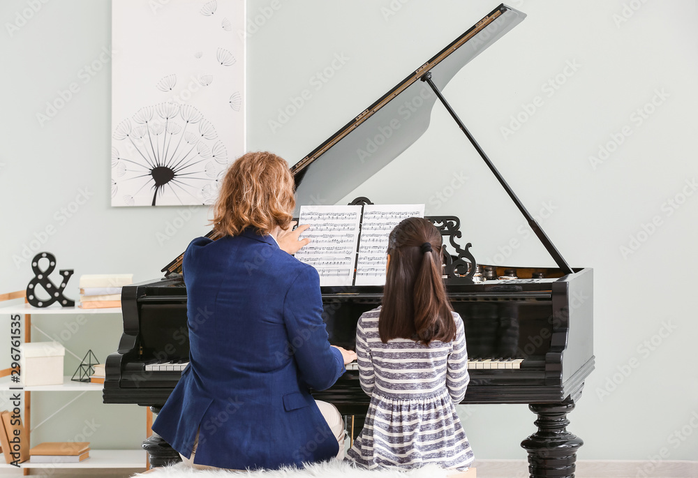 Man teaching little girl to play piano