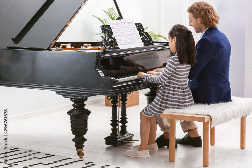 Man teaching little girl to play piano