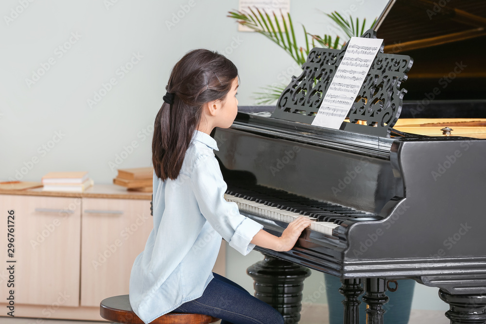 Little girl playing grand piano at home