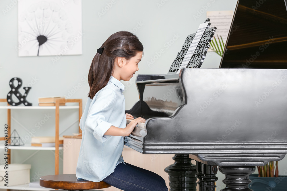 Little girl playing grand piano at home