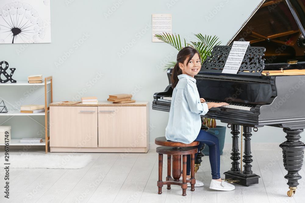 Little girl playing grand piano at home