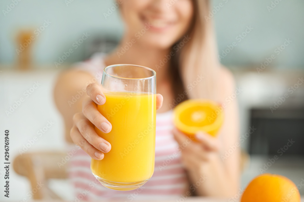 Young woman with healthy orange juice in kitchen, closeup. Diet concept